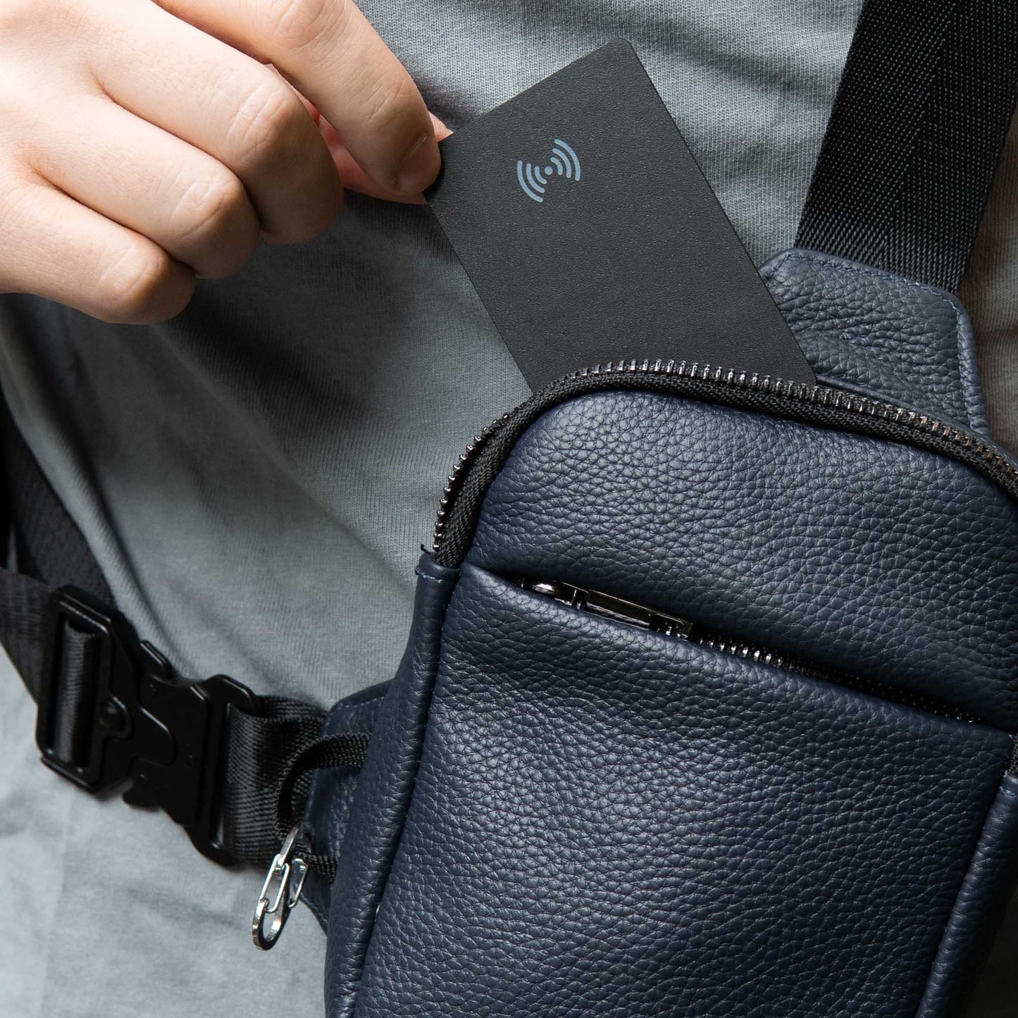 Person placing a card into a black leather bag with a textured surface.